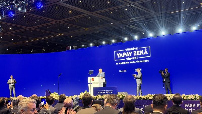 Türkiye Yapay Zekâ Zirvesi'nde kürsüde bir konuşmacı; arkadaki mavi panoda “13 Haziran 2026 · İstanbul” yazıyor, ön sıralarda dinleyiciler